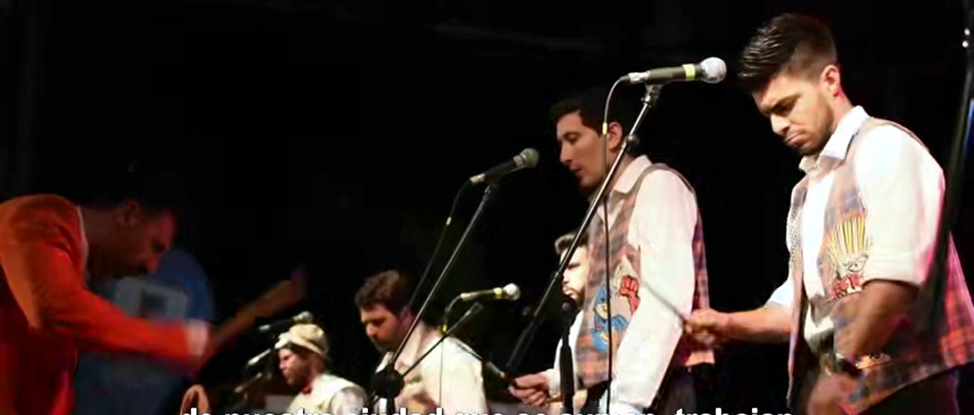 Banda de cumbia tocando en vivo sobre el escenario iluminado, con el público en primer plano