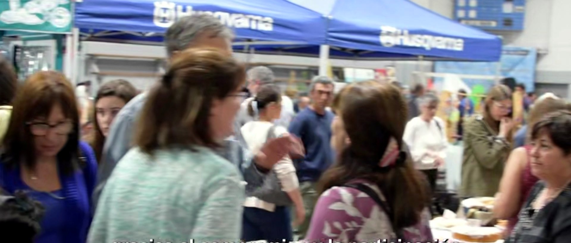 Público recorriendo los gazebos azules de la feria, con platos de comida en la mano